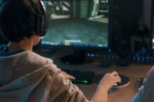 Teenager wearing a headset and playing online video games at home, 3D shooter games