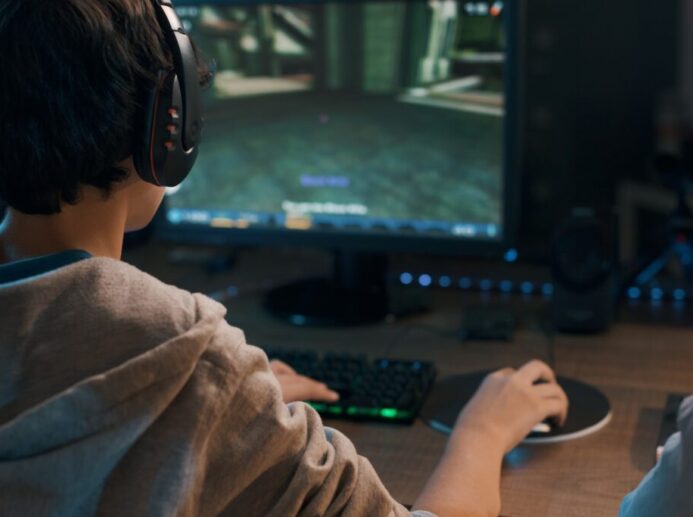 Teenager wearing a headset and playing online video games at home, 3D shooter games