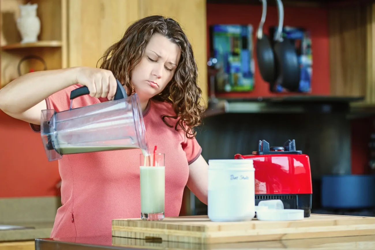 smutná žena si nalévá smoothie z mixéru