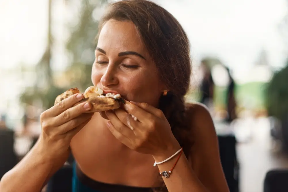 Žena si pochutnává na pizze.