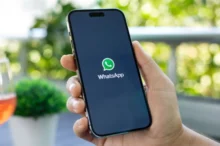 Ruka držící telefon s načítající se aplikací WhatsApp