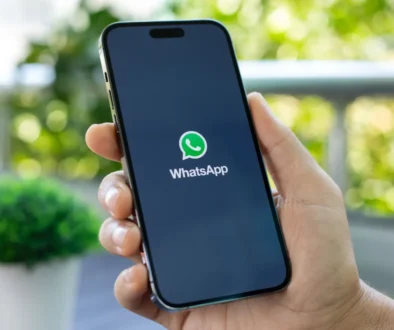 Ruka držící telefon s načítající se aplikací WhatsApp