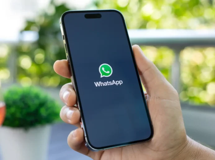 Ruka držící telefon s načítající se aplikací WhatsApp