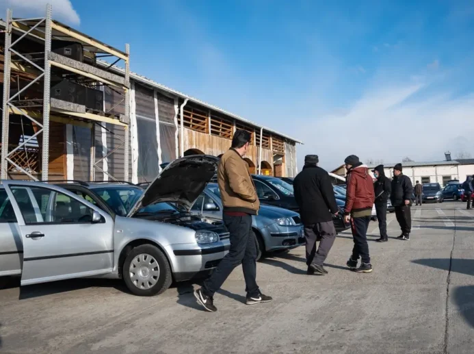 Autobazar, ve kterém se nachází několik lidí.