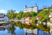 Hrad Rožmberk nad malebnou krajinou a řekou Vltava.