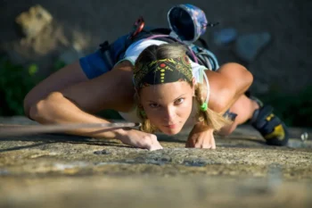 Žena lezoucí na skálu a focená shora