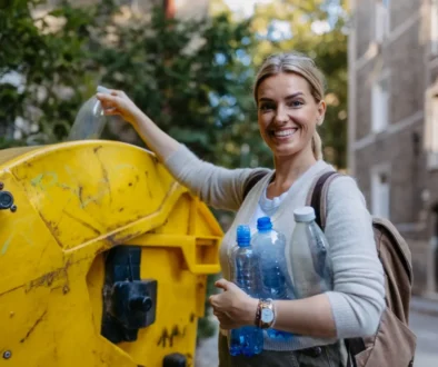 Žena vyhazující PET láhve do žlutého kontejneru