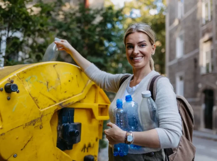 Žena vyhazující PET láhve do žlutého kontejneru