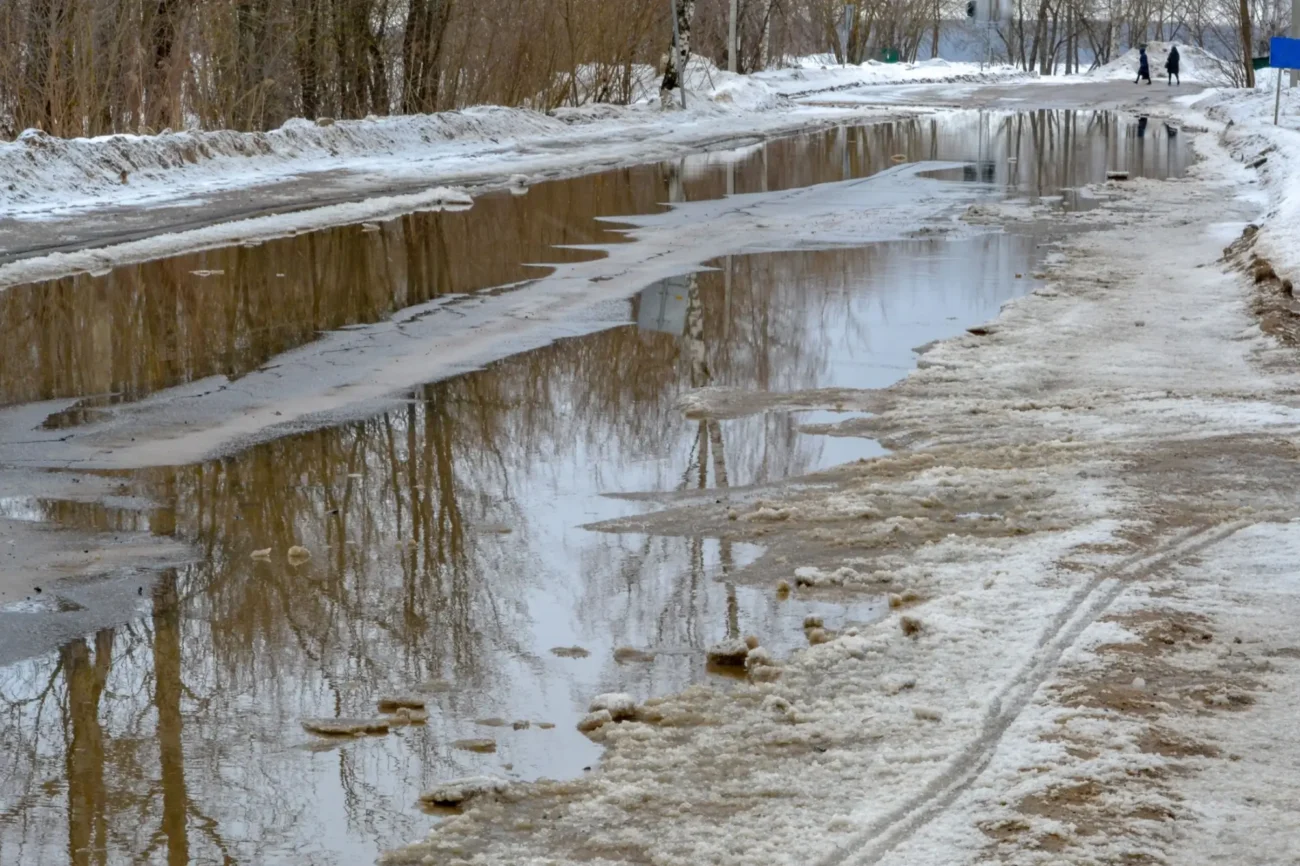 Silnice s tajícím sněhem a kalužemi