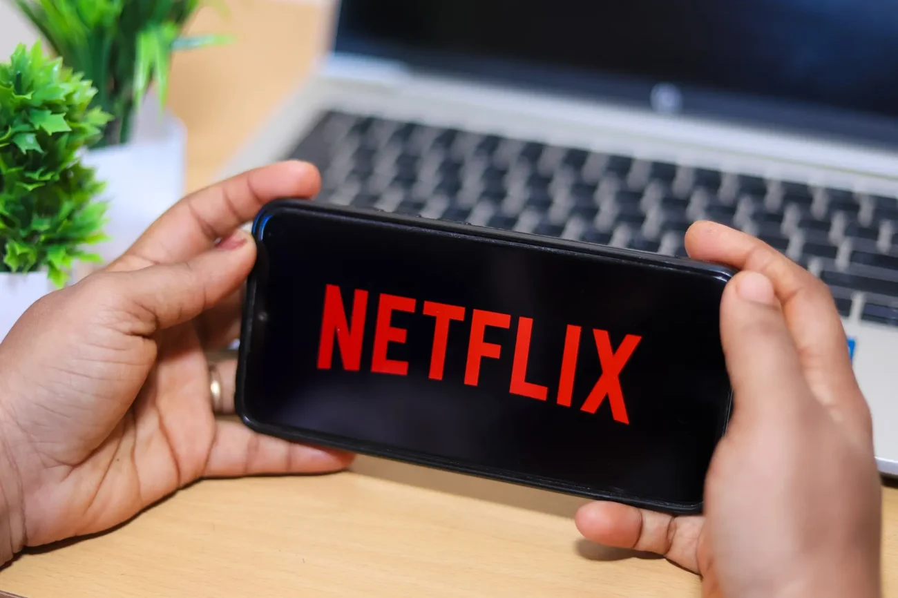 Ruce s telefonem, kde se spouští aplikace Netflix.