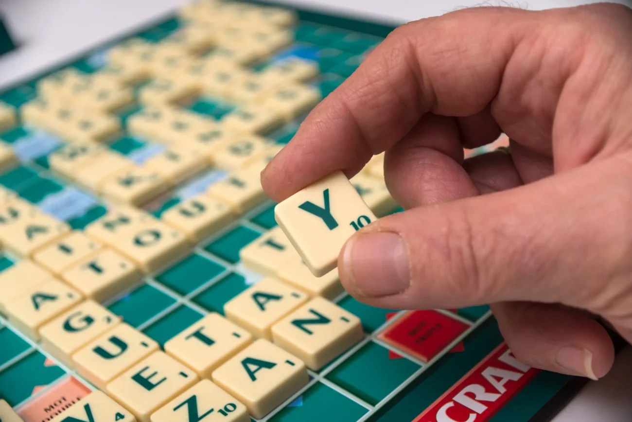 Člověk v ruce drží Scrabble kostičku. 