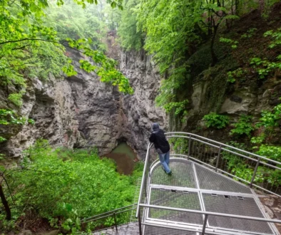 člověk se sklání nad jezírkem v Hranické propasti