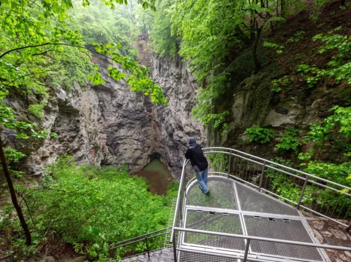 člověk se sklání nad jezírkem v Hranické propasti